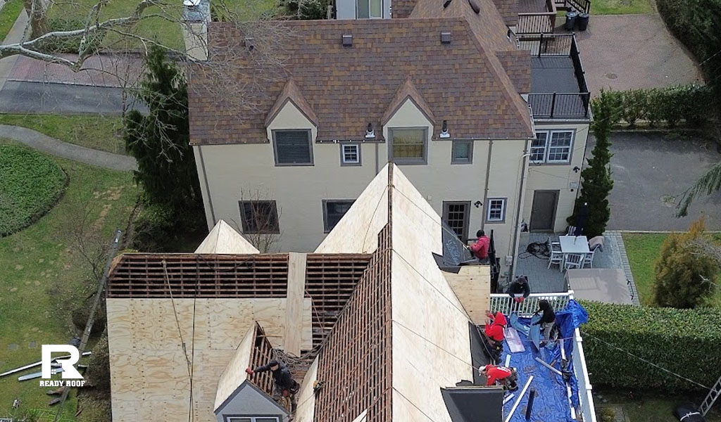 A large project showing roofers working in stages. Understanding when should you replace your roof can save money.