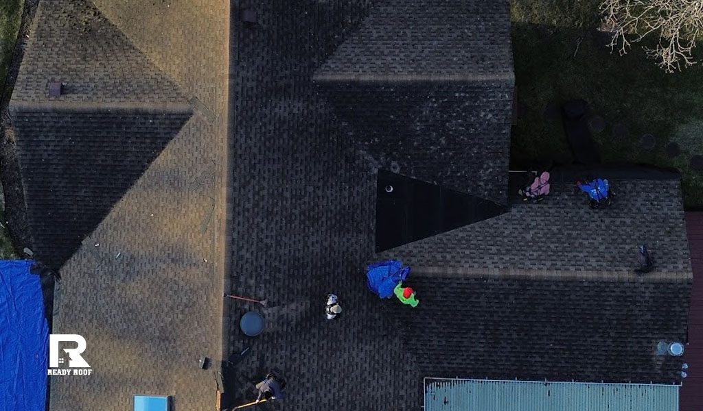 Roofing contractors working safely on a steep dark roof, installing the best roofing materials long island properties need for protection.