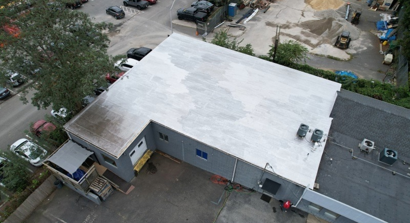 Two workers in high-visibility gear operate vacuum equipment to clear debris from a street manhole.