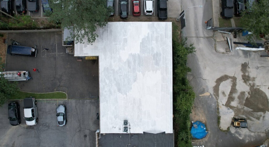 A technician wearing orange safety gloves guides a heavy-duty suction pipe into an open drain.