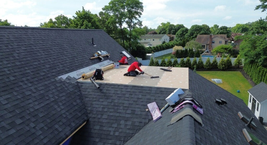 A technician wearing orange safety gloves guides a heavy-duty suction pipe into an open drain.