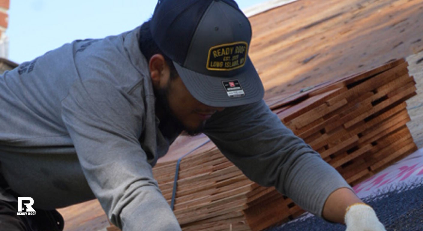 A Ready Roof worker prepares materials on a roof, a factor when determining your gutter installation cost on long island.