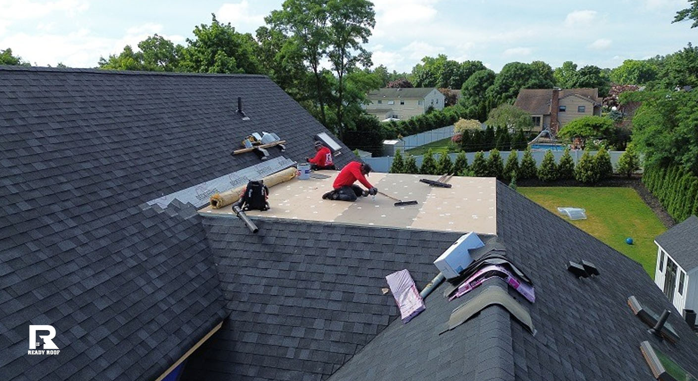 Two Ready Roof workers actively installing base materials during a residential flat roof repair.
