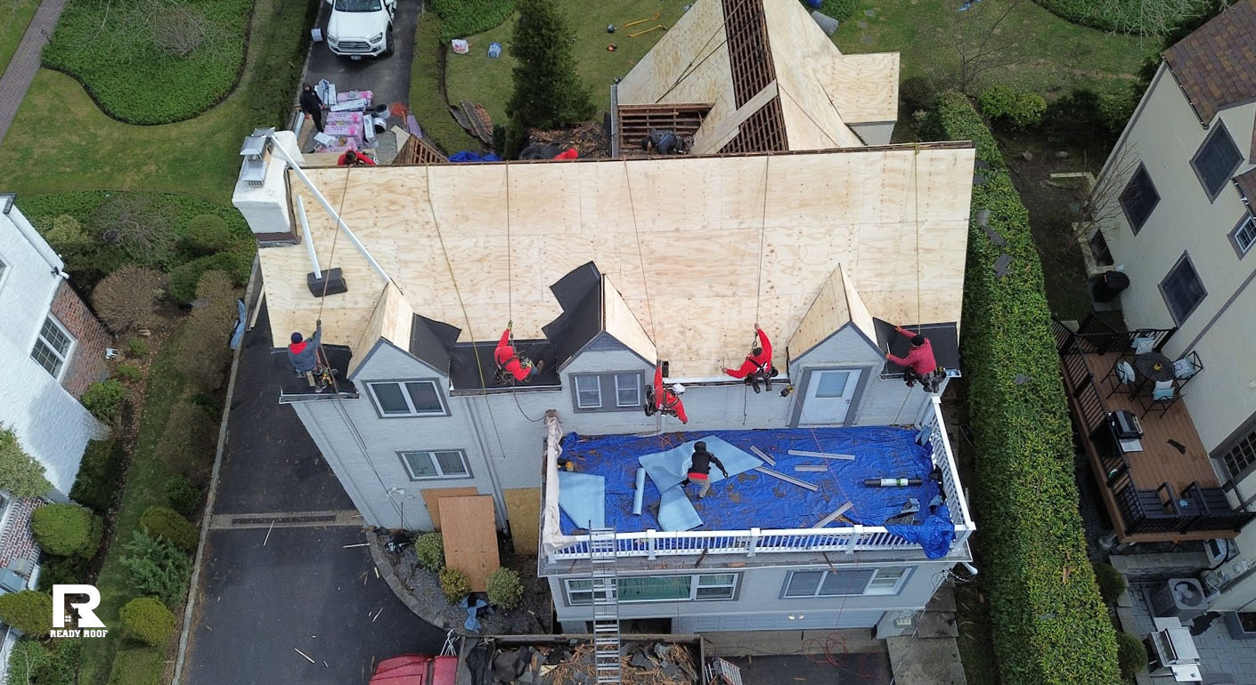 A roofing crew installs new plywood decking. Knowing when should you replace your roof prevents leaks.