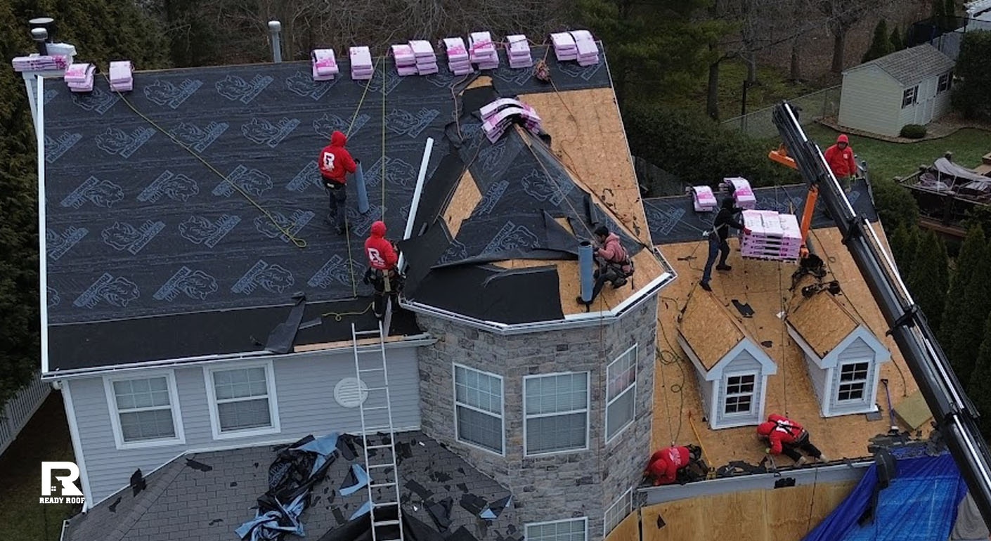 Crew installing underlayment on a large residential home, showcasing the extensive labor involved during a roof repair vs replacement project.